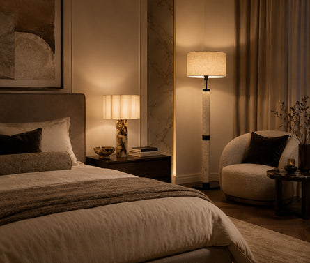 Tall sculptural travertine floor lamp casting a warm ambient light.
